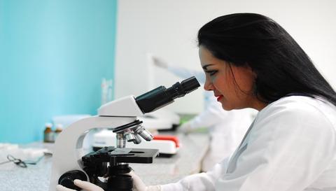 investigadora mirando por un microscopio 